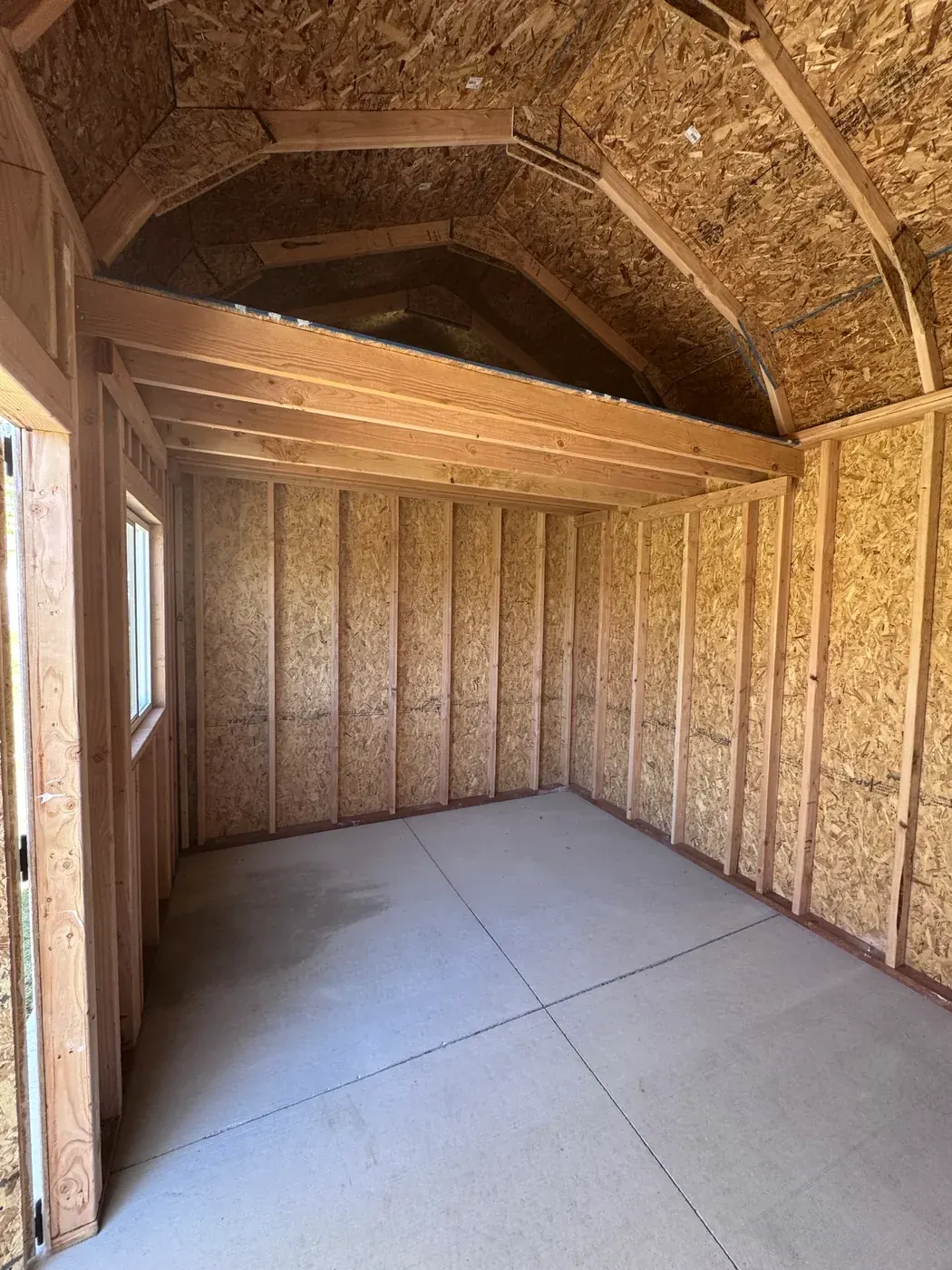 Interior of barn style shed showing gambrel roof framing and loft by ShedPro LLC
