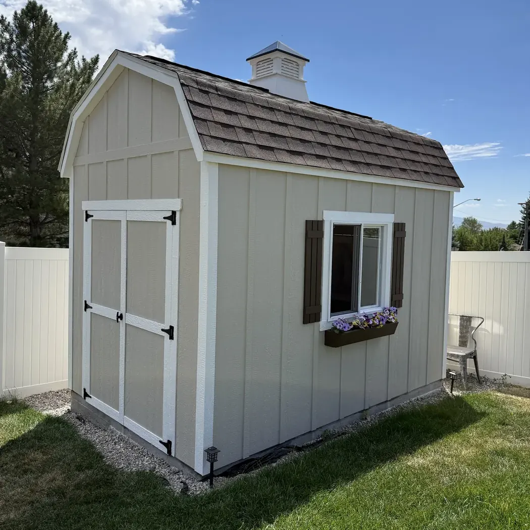 Almond barn style shed with a cupola, shutters and a flower box, built on-site by ShedPro LLC