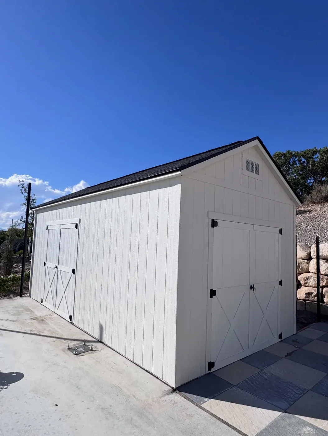 White A-frame gable shed with two sets of X-brace barn doors on a concrete pad, built by ShedPro LLC